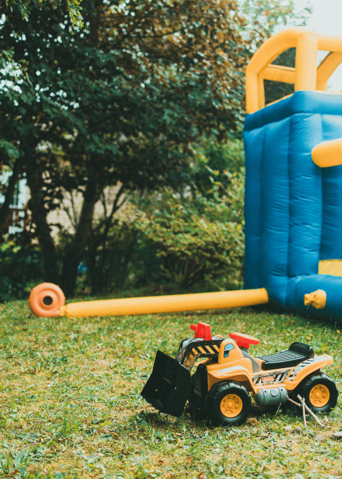Aufgeblasene Hüpfburg im Garten mit Spielzeugfahrzeug – perfekt für Kindergeburtstage und Familienfeiern in Wien - jetzt Hüpfburg mieten bei FA-Verleih.